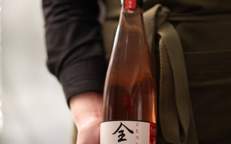 A staff member presents a bottle of Zenkuro Plum Sake at The George hotel. Served with the final course at the 2025 Sakura and Sake Dinner