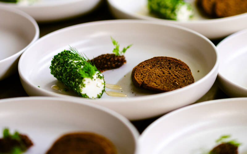 a collection of plates serving Goats Cheese Pumpernickel Spiced Honey & Marmalade Entree at the Sakura and Sake Dinner 2025